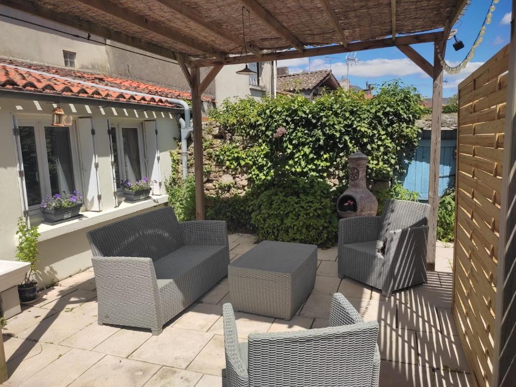 une terrasse avec des chaises en osier et une pergola dans l'établissement Maison de bourg spacieuse avec terrasse, à Palluau