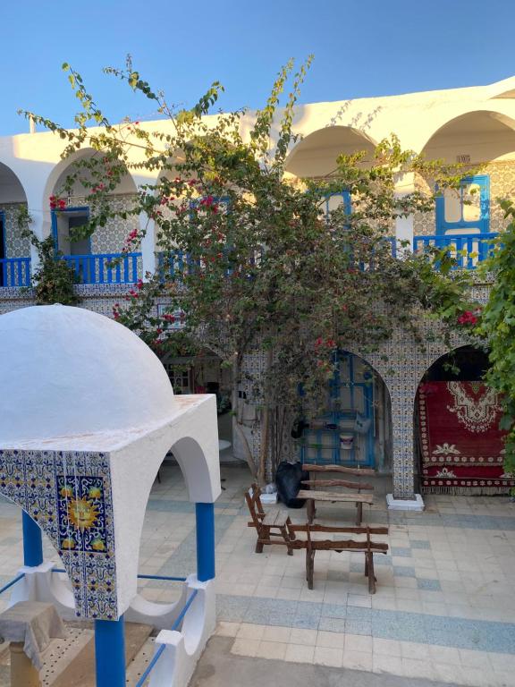 a courtyard with a tree and a bench and a building at Hôtel Sindbad in Houmt Souk
