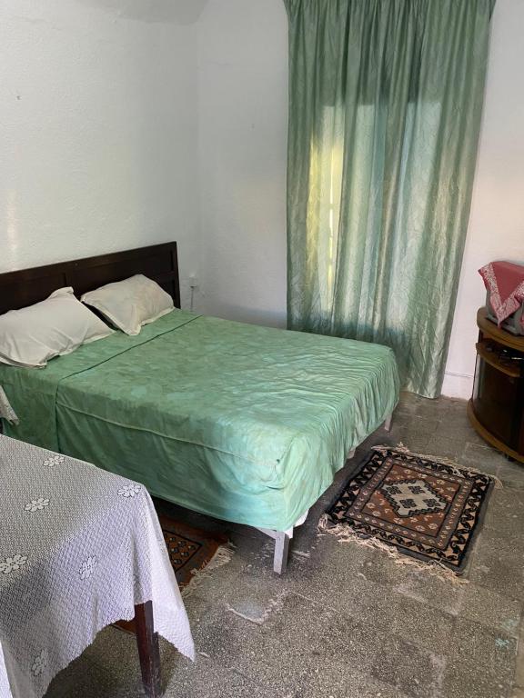 a bedroom with a bed with a green comforter at Hôtel Sindbad in Houmt Souk