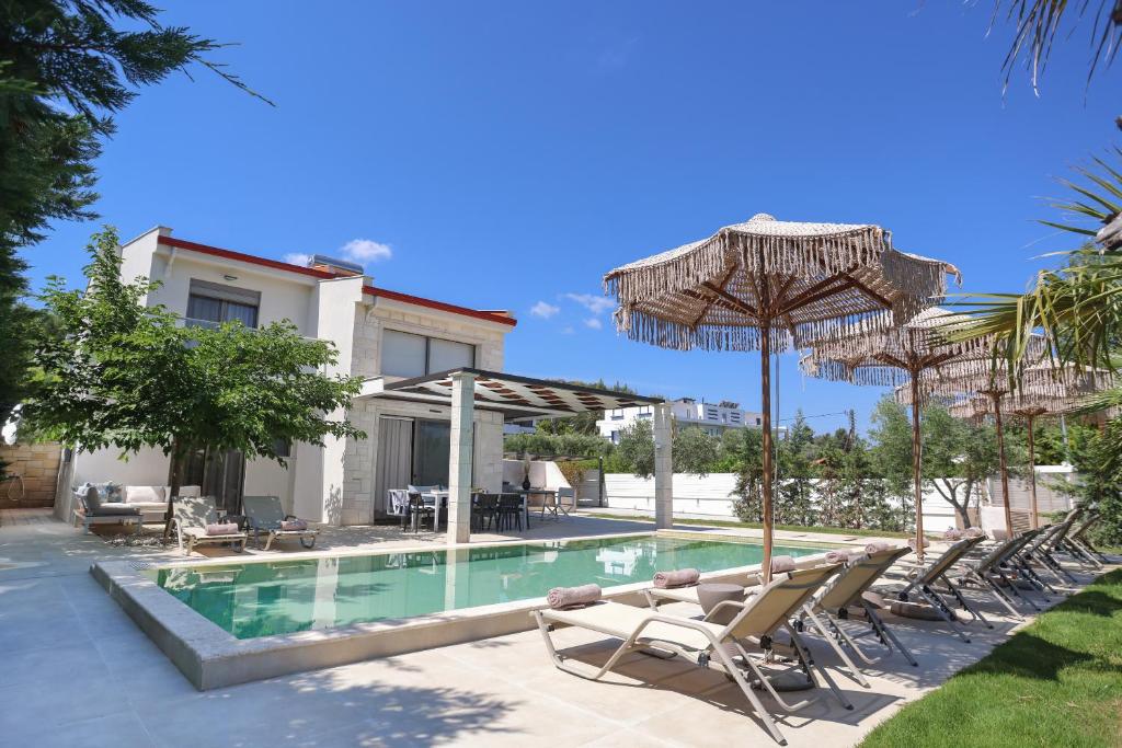 a swimming pool with lounge chairs and umbrellas at W Villas Halkidiki in Pefkochori