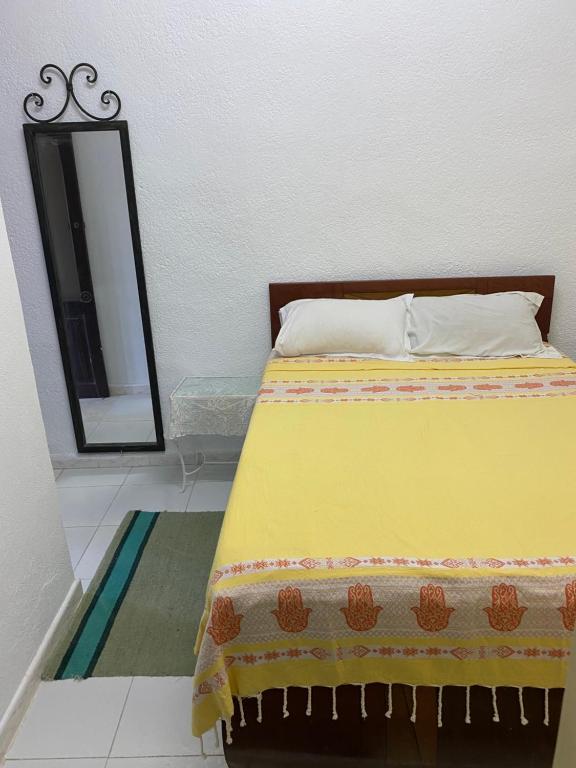 a bed with a yellow blanket and a mirror at Hôtel Sindbad in Houmt Souk