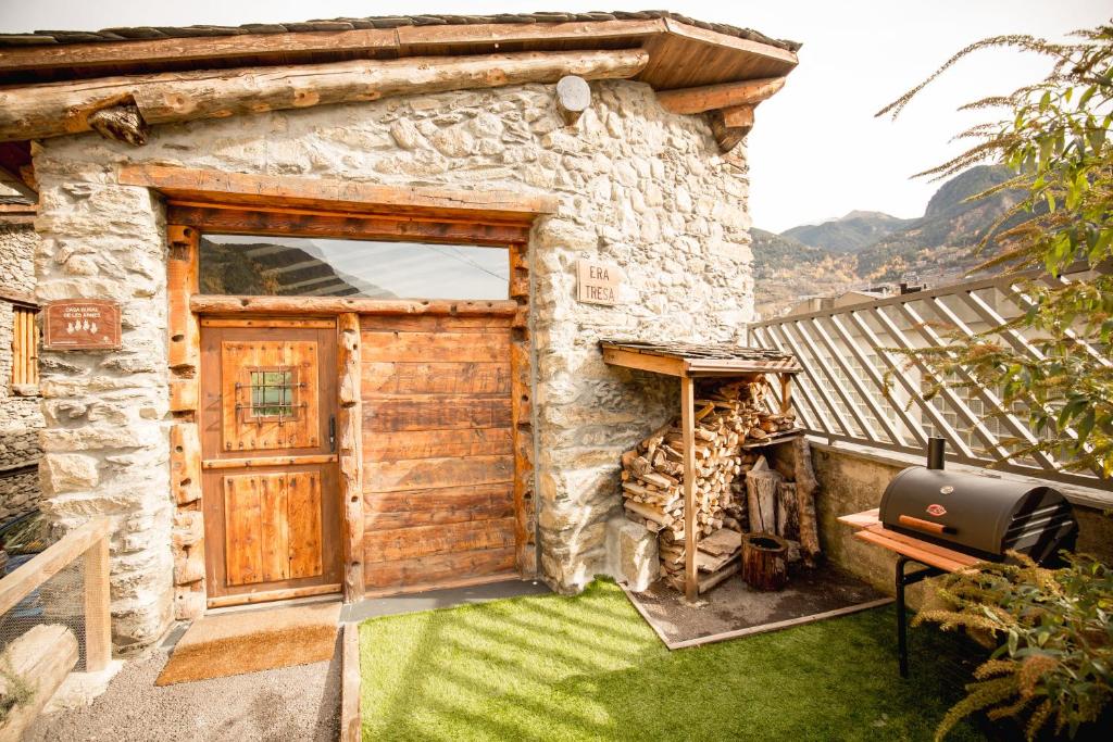 a stone house with a wooden door and a grill at R de Rural - Casa Rural de les Arnes in Encamp