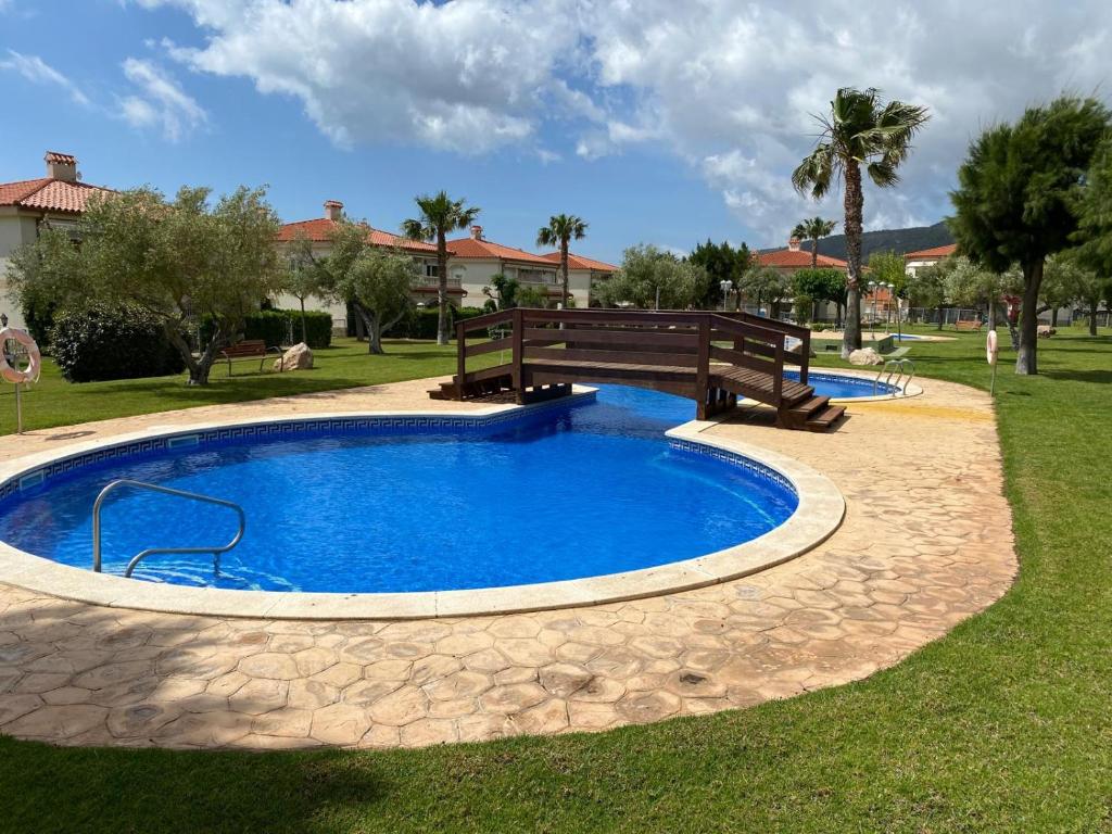 a swimming pool with a wooden bridge over it at La casita de mi hermana in Miami Platja
