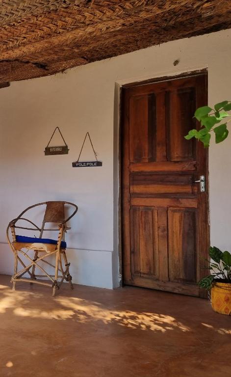 an old wooden door and a chair in a room at Sunny House Paje in Paje