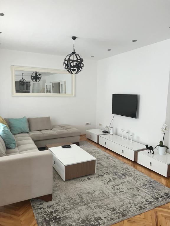 a white living room with a couch and a tv at Luxury 2 Apartment in Bijelo Polje