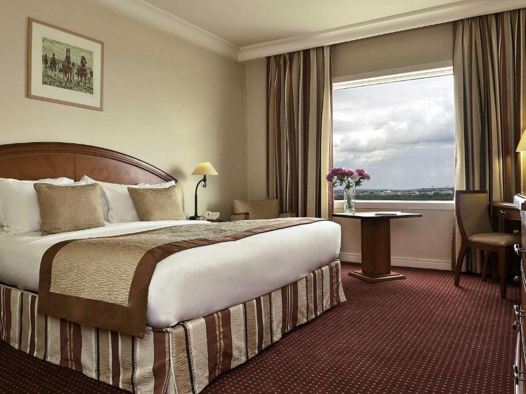 a hotel room with a bed and a large window at Pullman Bucharest World Trade Center in Bucharest