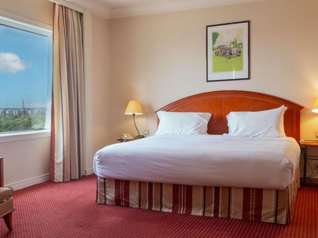 a hotel room with a large bed and a window at Pullman Bucharest World Trade Center in Bucharest