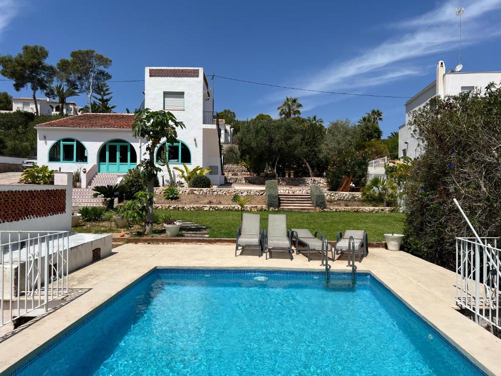 a swimming pool with two chairs and a house at Villa tosalet in Jávea