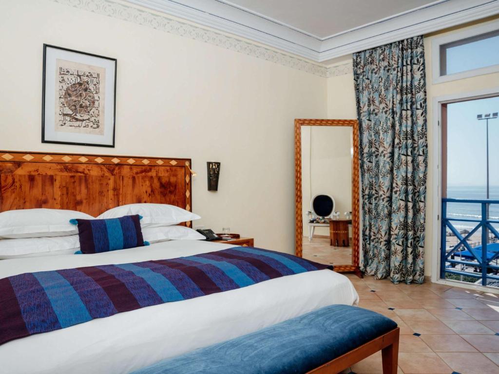 a bedroom with a bed and a large window at Le Médina Essaouira Thalassa Sea & Spa - MGallery Collection in Essaouira