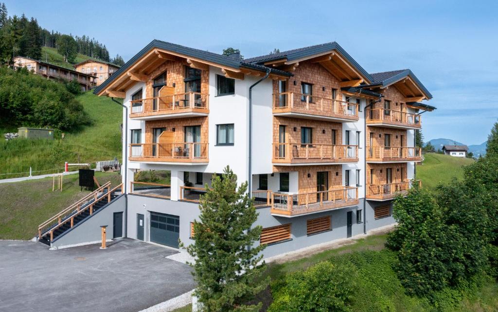 an apartment building with wooden balconies and a parking lot at Höflehner Premium Gumpen Lodge in Haus im Ennstal