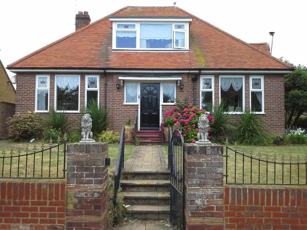 a brick house with a black gate and flowers at Nest Guesthouse in Margate