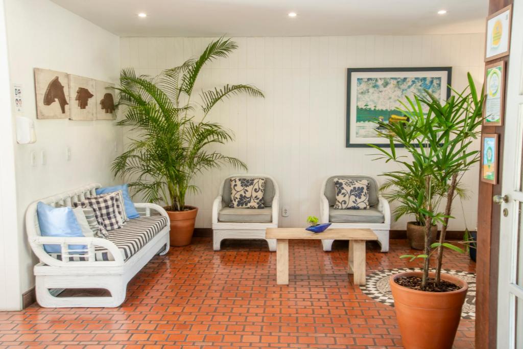 a living room with three chairs and a table and plants at Manacá Pousada Parque in Arraial d'Ajuda