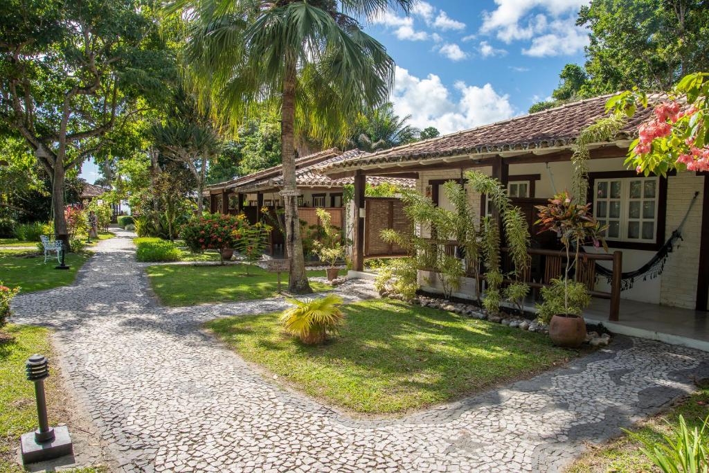 a house with a garden and a pathway at Manacá Pousada Parque in Arraial d'Ajuda