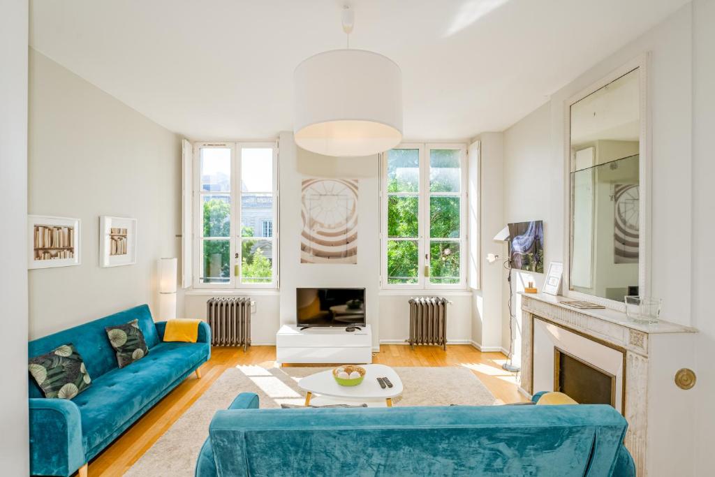 a living room with a blue couch and a fireplace at Appartement T3 de Prestige proche du Jardin Public de Bordeaux in Bordeaux