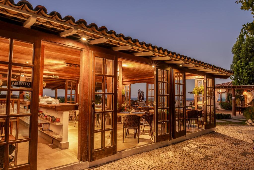 a wooden house with glass doors and a table at Manacá Pousada Parque in Arraial d'Ajuda