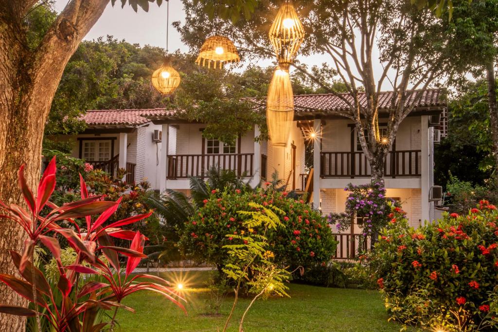 a house with flowers and lights in a yard at Manacá Pousada Parque in Arraial d'Ajuda