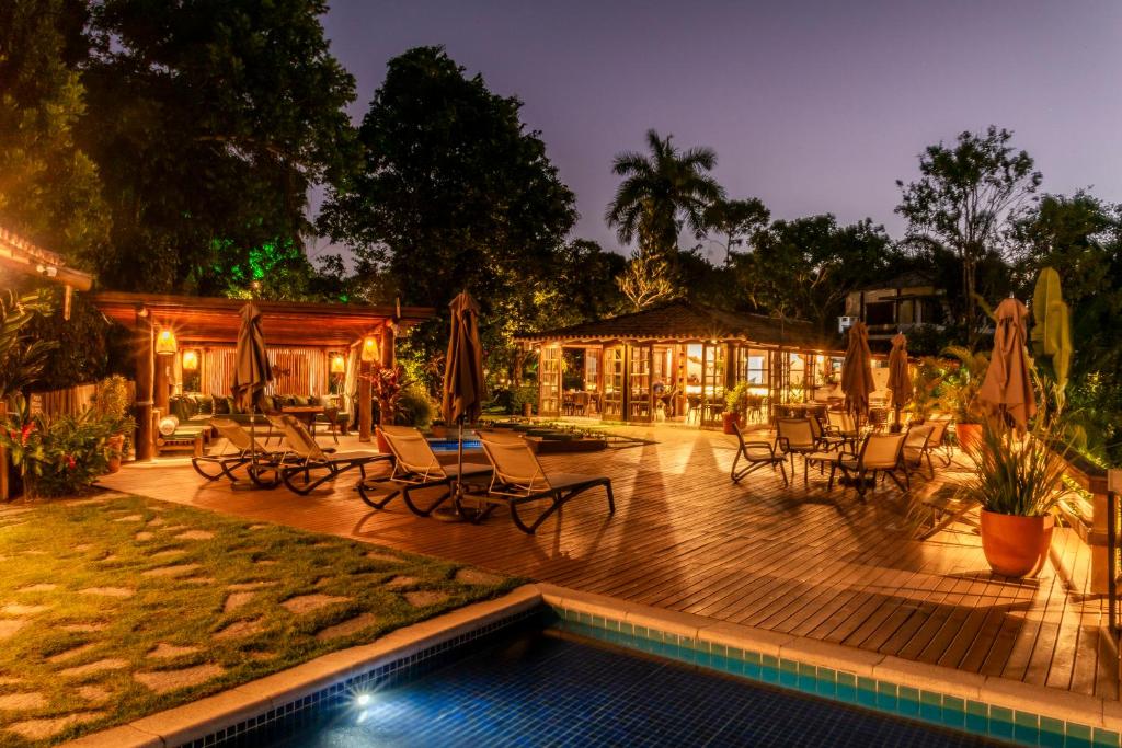 a patio with chairs and a pool at night at Manacá Pousada Parque in Arraial d'Ajuda