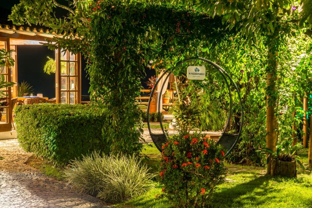 a garden with a swing and some plants and flowers at Manacá Pousada Parque in Arraial d'Ajuda