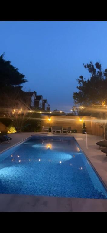 a large swimming pool in a backyard at night at Stranraer House and pool in Selsey