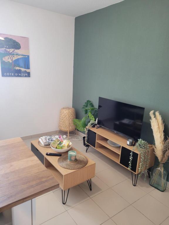 a living room with a tv and a table at Charmant T2 Climatisé proche du centre et des commerces - Gare à 15 minutes in Toulon