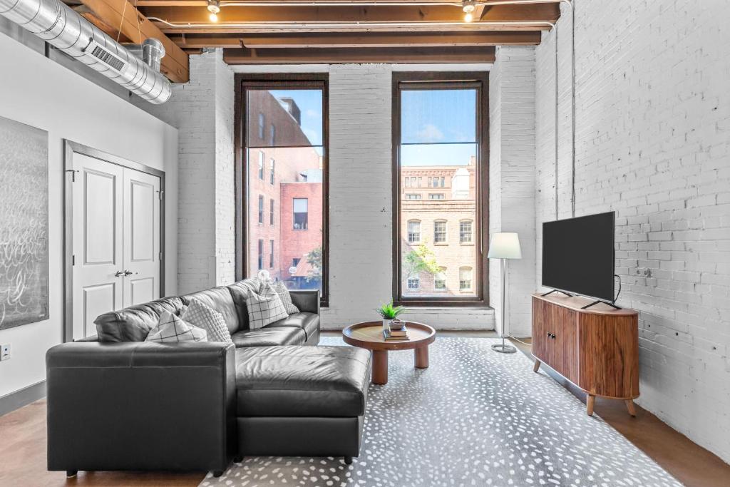 a living room with a couch and a tv at Stylish Riverfront Loft- Gym - Walk to Arch, Casino, Conventions in Saint Louis