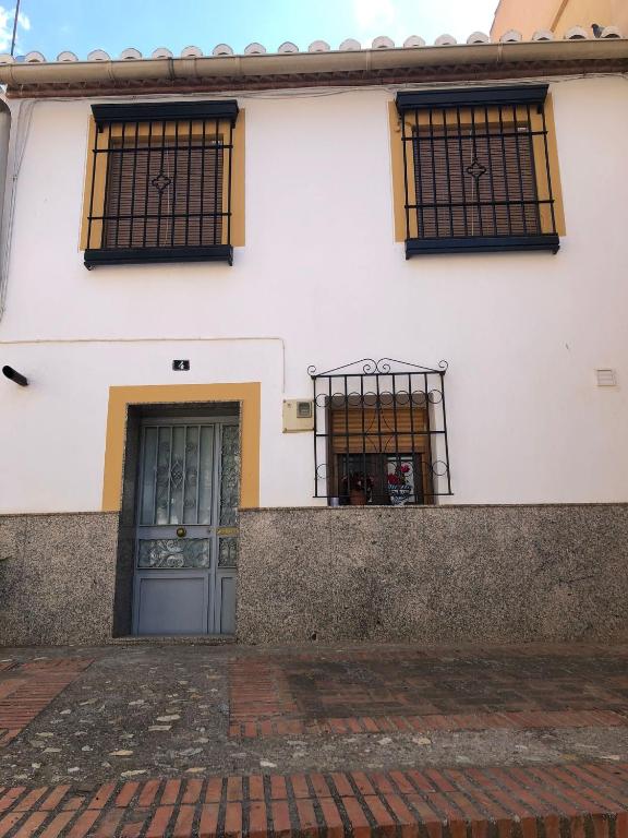 a white building with a door and two windows at La Gloria in Guadix