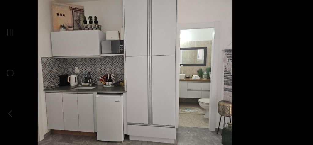 a white kitchen with a sink and a toilet at Studio Caroline in Eilat