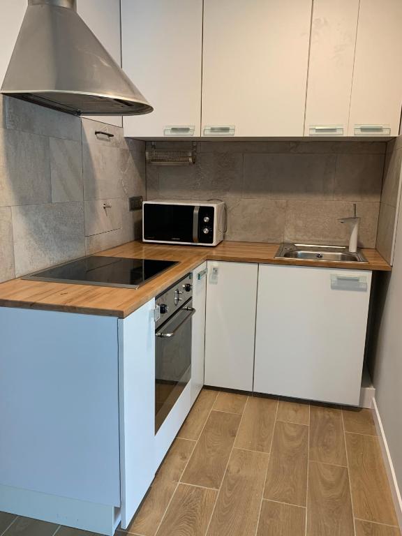 a kitchen with white cabinets and a stove and a microwave at T2 proche des 2 Jumeaux in Hendaye