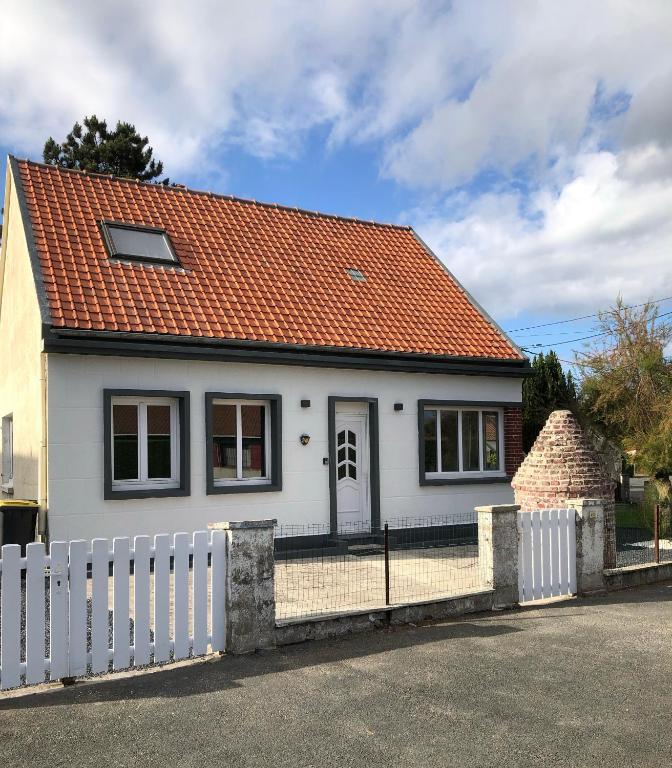 une maison blanche avec un toit orange et une clôture dans l'établissement Gite du vieux Puits, à Merlimont