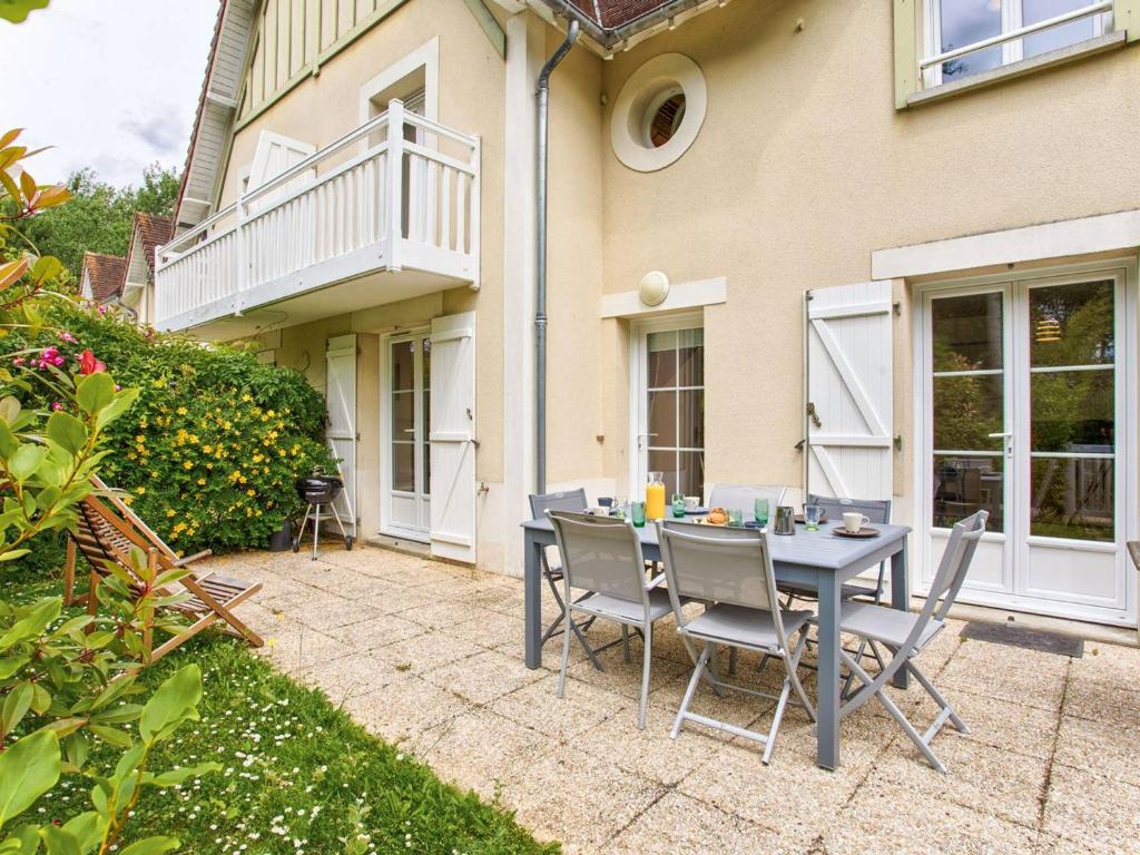 un patio avec une table et des chaises devant une maison dans l'établissement Maison de vacances pour 6 personnes à 600m de la plage avec terrasse et jardin, idéale en famille - FR-1-788-13, à Merville-Franceville-Plage