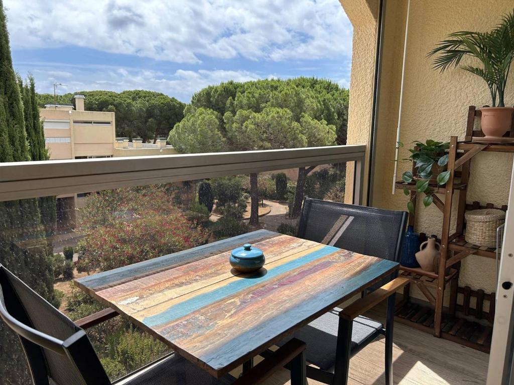 d'une table en bois sur un balcon avec vue. dans l'établissement Studio climatisé à 200m de la plage avec balcon, parking et ménage inclus - Bormes-les-Mimosas - FR-1-251-836, à Bormes-les-Mimosas