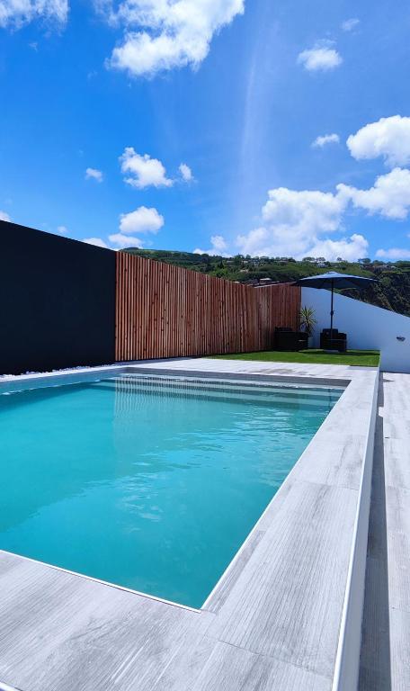 a swimming pool with blue water and a wooden fence at Azure Sunset in Ponta Delgada