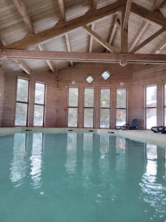 - une piscine d'eau bleue dans une chambre avec fenêtres dans l'établissement Chalet By Sophie Superdevoluy avec piscine, à Superdevoluy