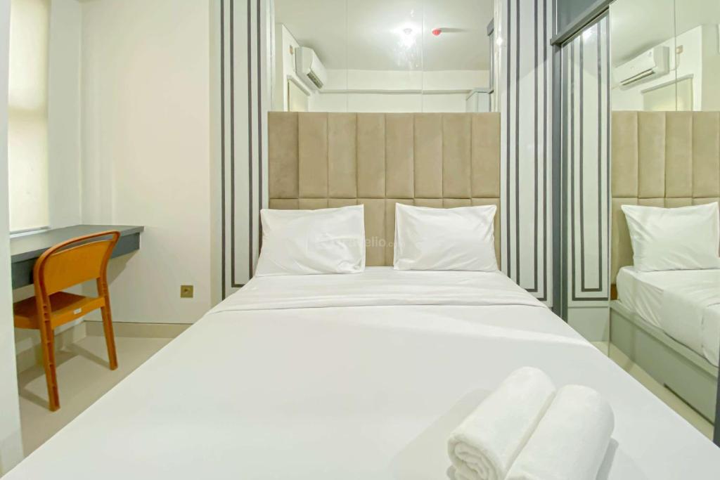 a bedroom with a large white bed and a desk at Comfy and Tidy Studio Transpark Cibubur Apartment By Travelio in Depok