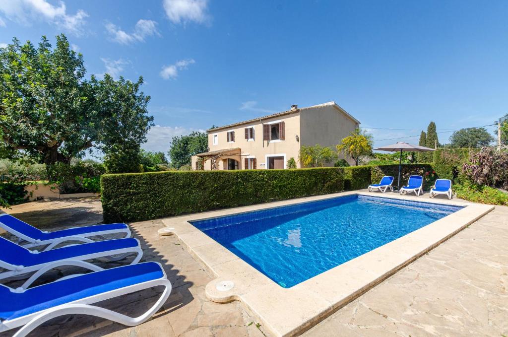 a swimming pool with chairs and a house at YourHouse Can Galeri villa in Felanitx