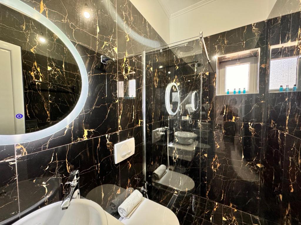 a bathroom with a black tiled wall with a mirror at Dine Hotel in Ksamil