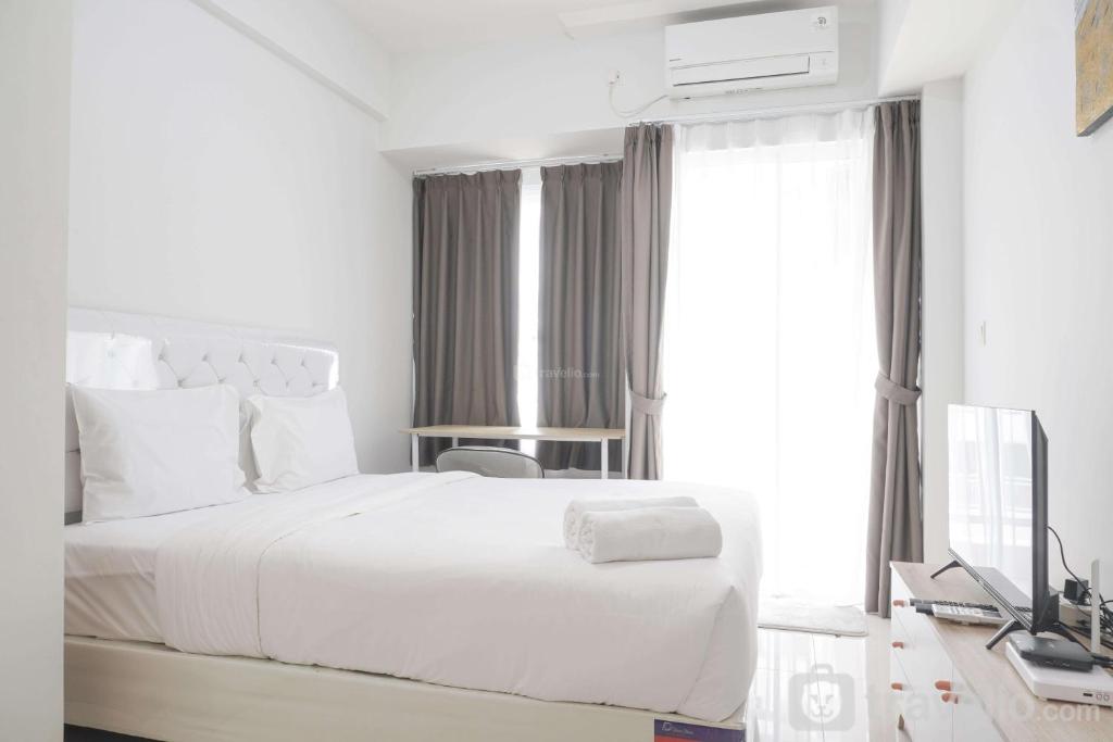 a white bedroom with a white bed and a desk at Modern Look Studio Room at Citra Living Apartment By Travelio in Jakarta