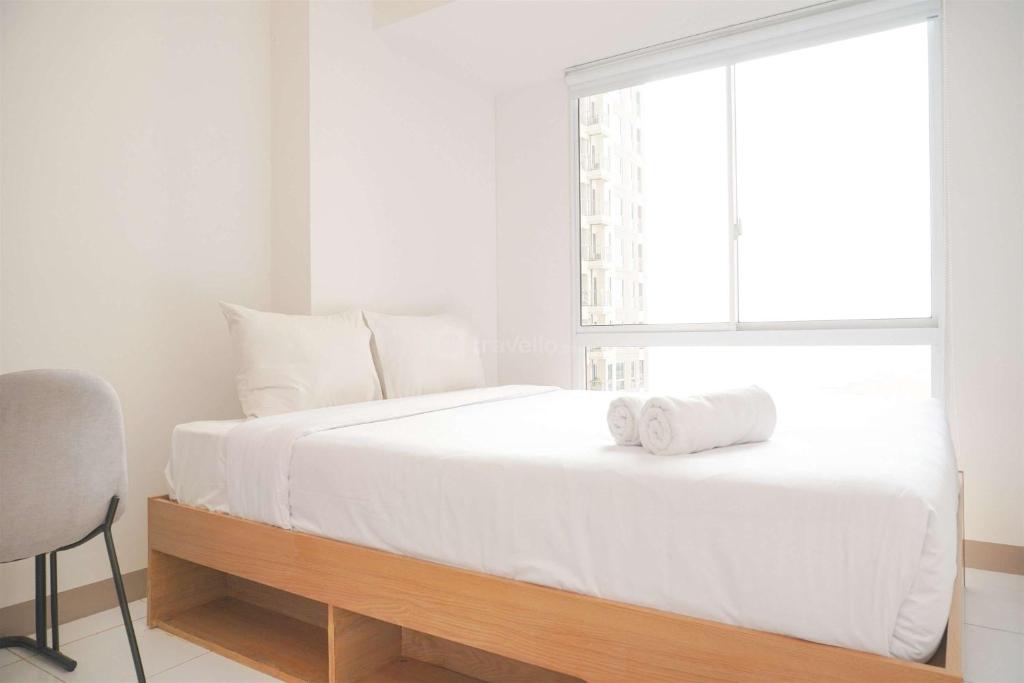 a white bedroom with a large bed with a window at Well Furnished and Restful 2BR Tokyo Riverside PIK 2 Apartment By Travelio in Rawalembang