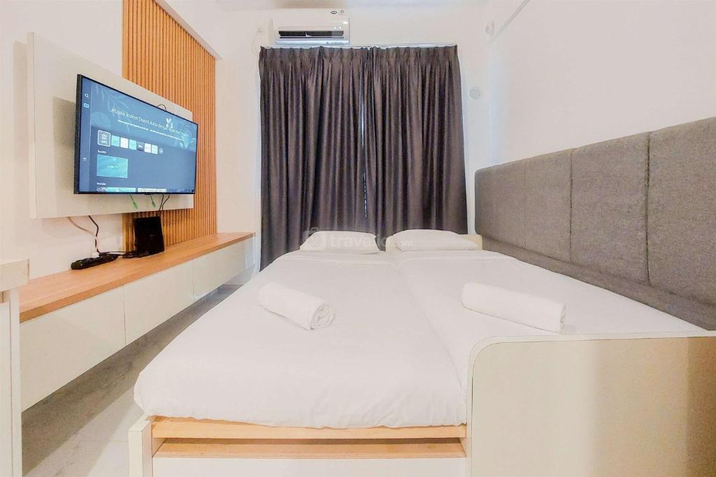 ein Schlafzimmer mit großem Bett und Flachbildfernseher in der Unterkunft Cozy Living Studio Sky House BSD Apartment near AEON Mall By Travelio in Tangerang