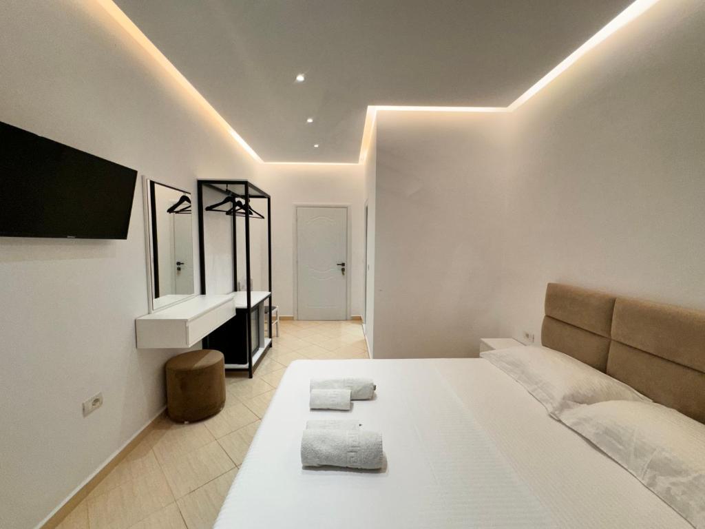 a bedroom with a large white bed and a mirror at Dine Hotel in Ksamil