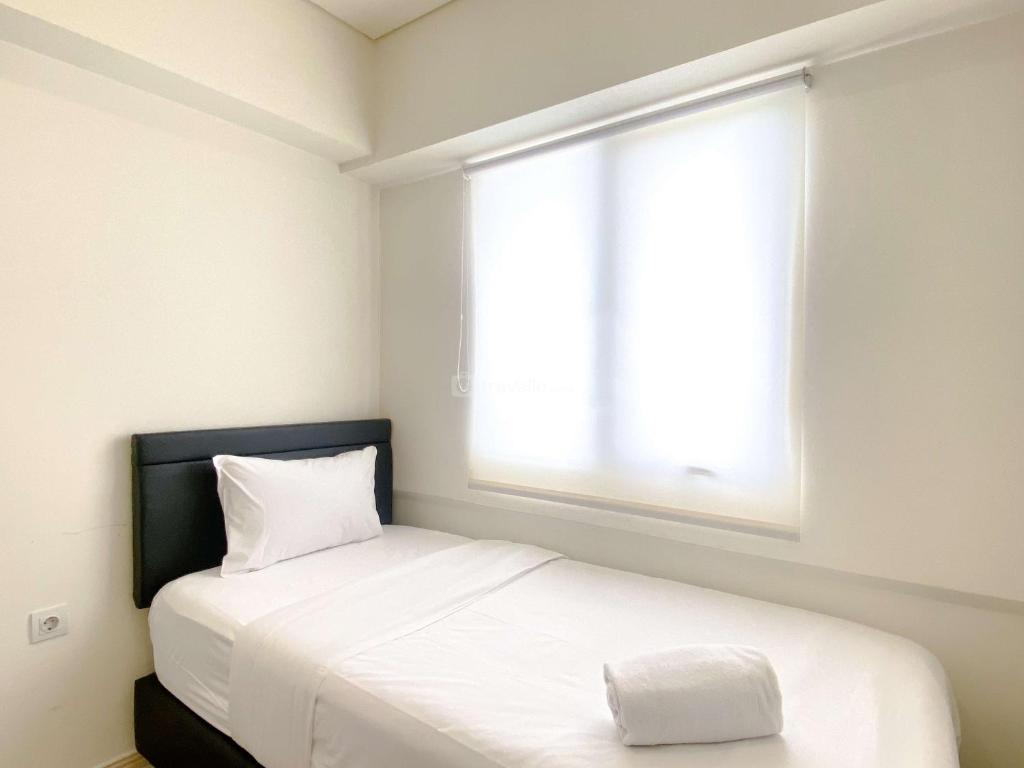 芝卡朗Comfortable and Spacious 3BR Meikarta Apartment By Travelio的一间卧室，里面有一张白色床，窗外是一扇窗户。