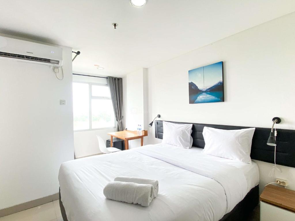 a bedroom with a large white bed and a desk at Enjoy Living Studio at Enviro Apartment By Travelio in Cikarang