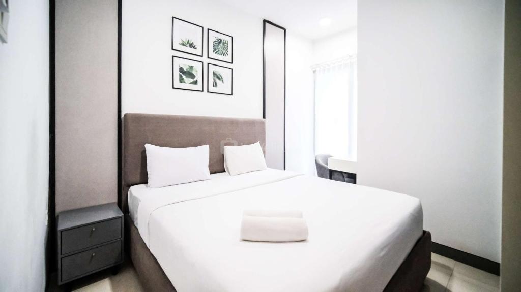 a bedroom with a large bed with white sheets at Comfortable Living 2BR at Anderson Supermall Mansion Apartment By Travelio in Surabaya