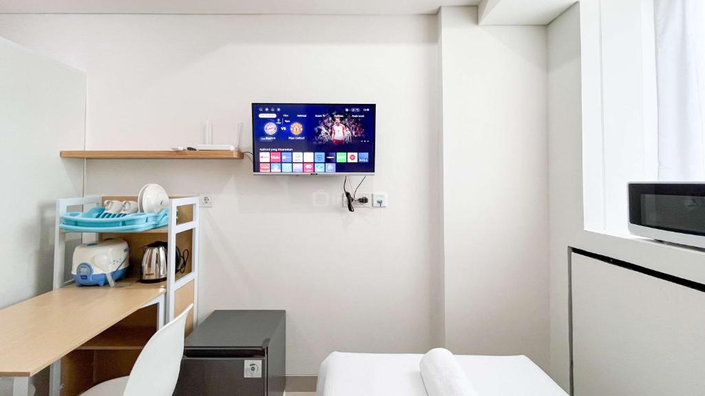 a living room with a tv on the wall at Tranquil Studio (No Kitchen) Apartment Bandaraya - Tallasa City Makassar By Travelio in Pacinongong