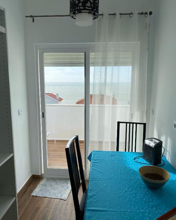 a dining room with a blue table with a view of the ocean at Casa Praia do Sul in Ericeira