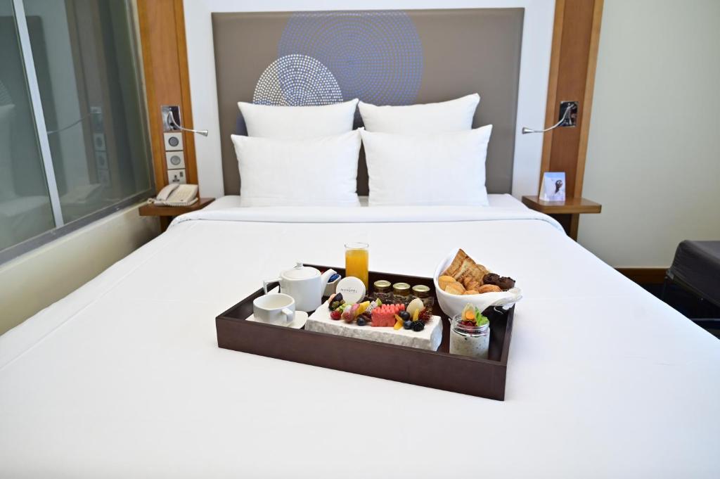 a tray of food on a bed in a hotel room at Novotel Fujairah in Fujairah