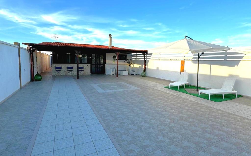 a patio with two white chairs and an umbrella at Villa Hermosa Beach in Margherita di Savoia