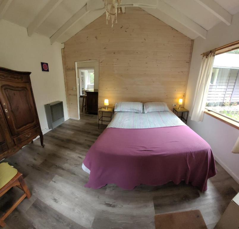 Un dormitorio con una cama grande con una manta morada. en Casas La Violeta, en Villa La Angostura