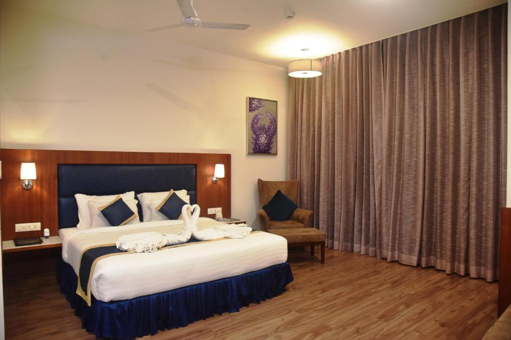 Una habitación de hotel con una cama grande y una silla. en ARIENA - The Boutique Hotel, en Raipur
