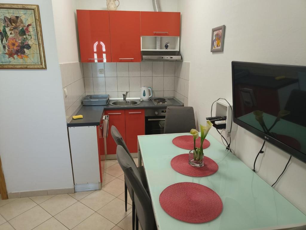 a kitchen with red cabinets and a table with a vase on it at apartman Ante in Kaštela